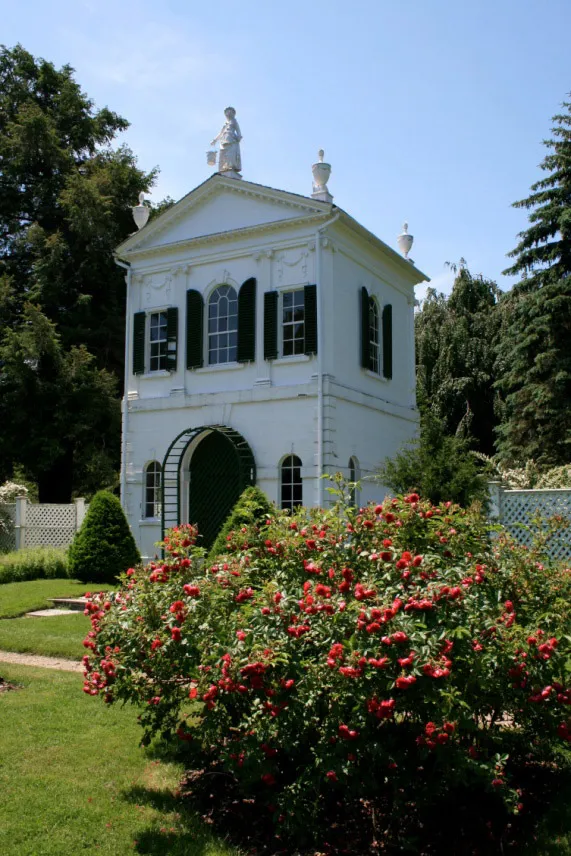 The white garden house among blooming shrubs